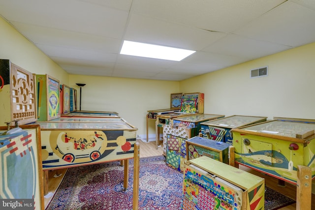 recreation room featuring wood finished floors, a paneled ceiling, and visible vents