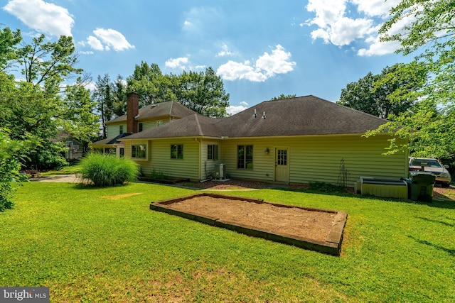 rear view of house featuring a shingled roof, a lawn, and a chimney