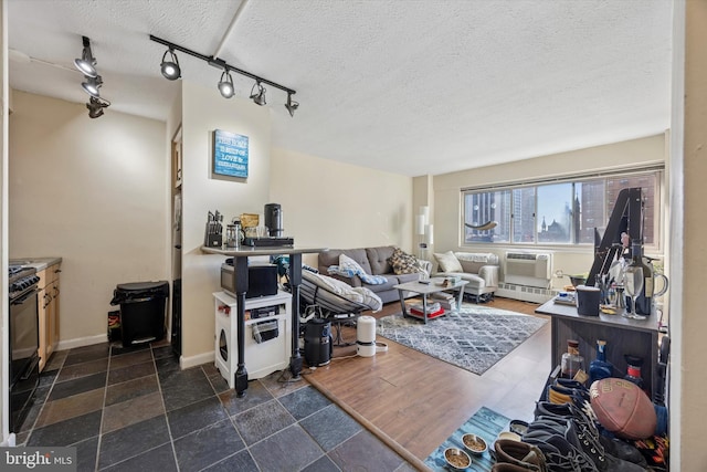 living area featuring an AC wall unit, dark wood-style floors, baseboards, and a textured ceiling