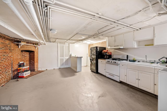 interior space featuring open shelves, white gas range oven, freestanding refrigerator, white cabinetry, and a sink