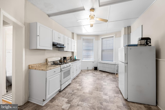 kitchen with under cabinet range hood, radiator heating unit, white appliances, white cabinets, and light countertops