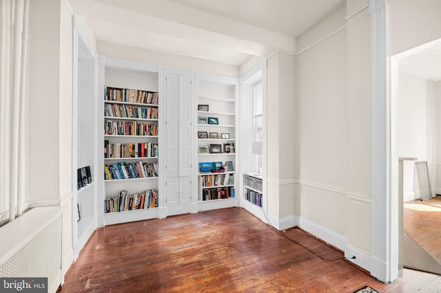 interior space featuring built in features, baseboards, radiator heating unit, and hardwood / wood-style flooring