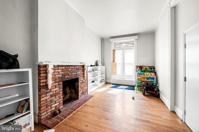 rec room featuring wood-type flooring and a brick fireplace