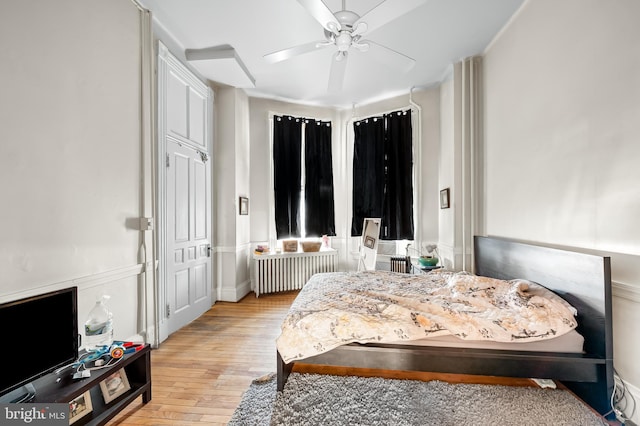 bedroom with radiator, light wood-style flooring, and a ceiling fan