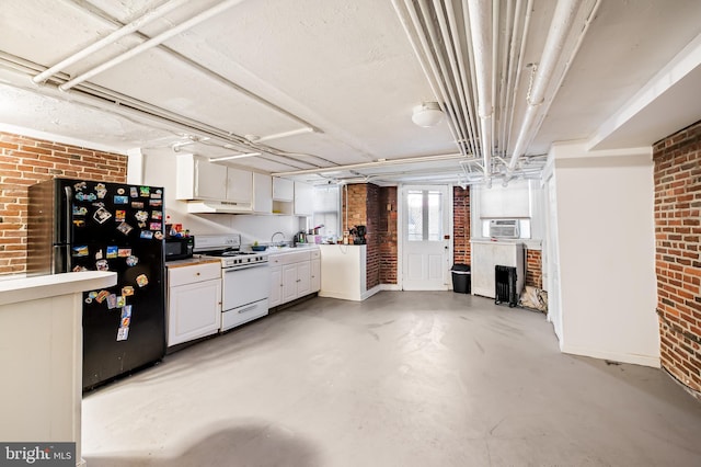 interior space with brick wall, black appliances, and concrete floors