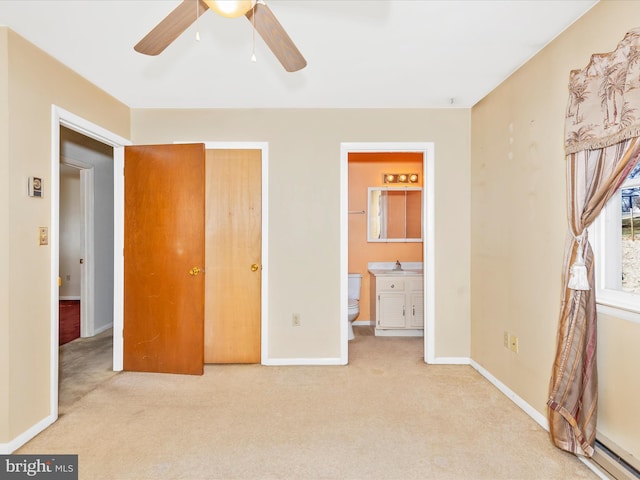 unfurnished bedroom with a baseboard heating unit, ensuite bath, baseboards, light colored carpet, and ceiling fan