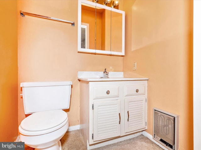 half bath with vanity, toilet, heating unit, and baseboards