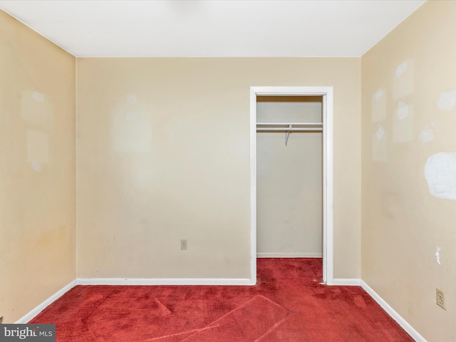 unfurnished bedroom with a closet, baseboards, a spacious closet, and carpet flooring