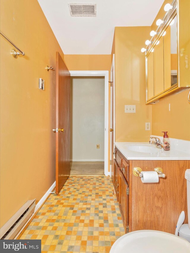 bathroom with vanity, baseboards, visible vents, a baseboard heating unit, and toilet