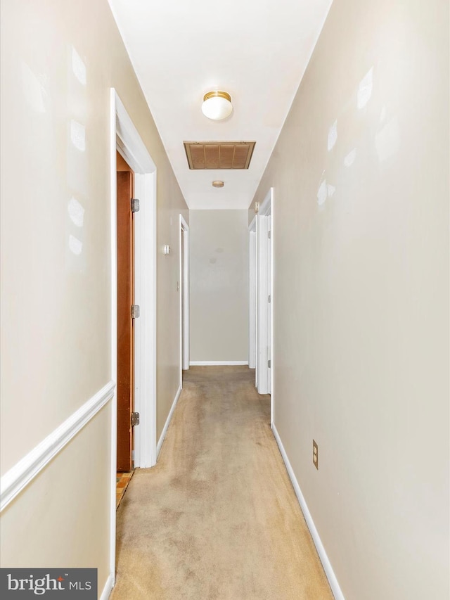 hallway featuring visible vents, light colored carpet, and baseboards