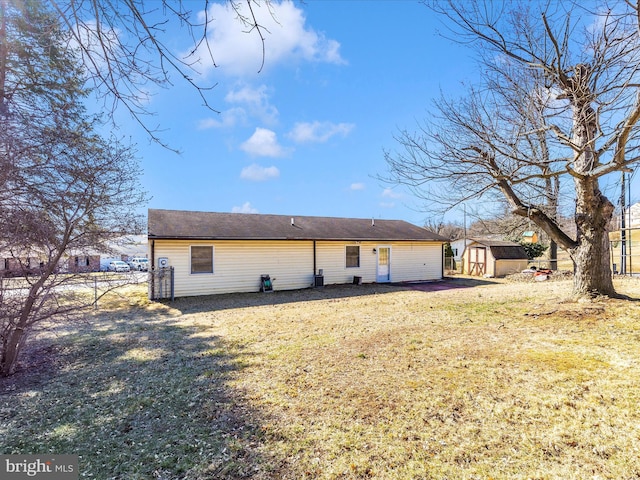 back of property with fence, a lawn, an outdoor structure, and a shed