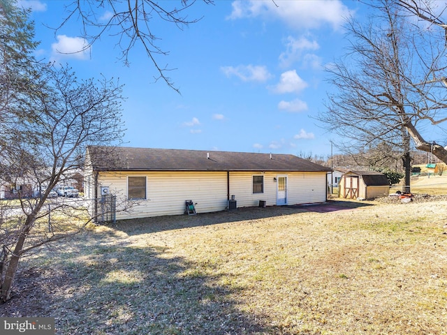 back of house featuring a yard, a shed, and an outdoor structure