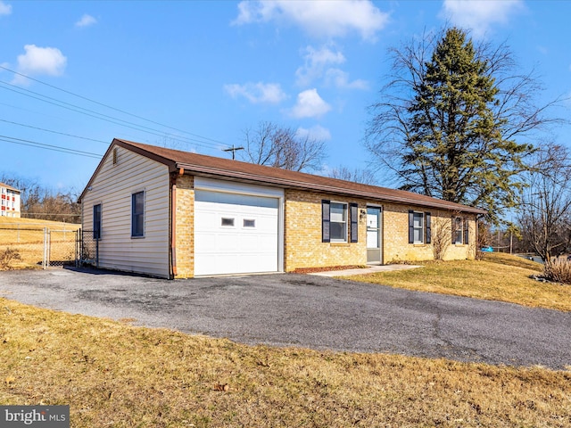 single story home featuring driveway, fence, a front yard, an attached garage, and brick siding