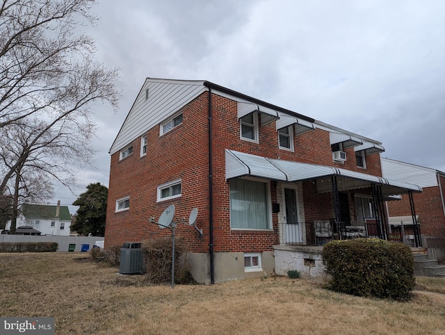 exterior space with brick siding, covered porch, central AC unit, and a front lawn