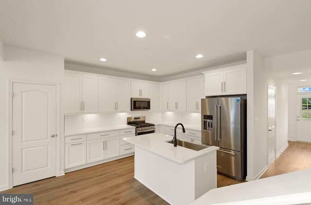 kitchen featuring light wood-style flooring, white cabinets, stainless steel appliances, and a sink