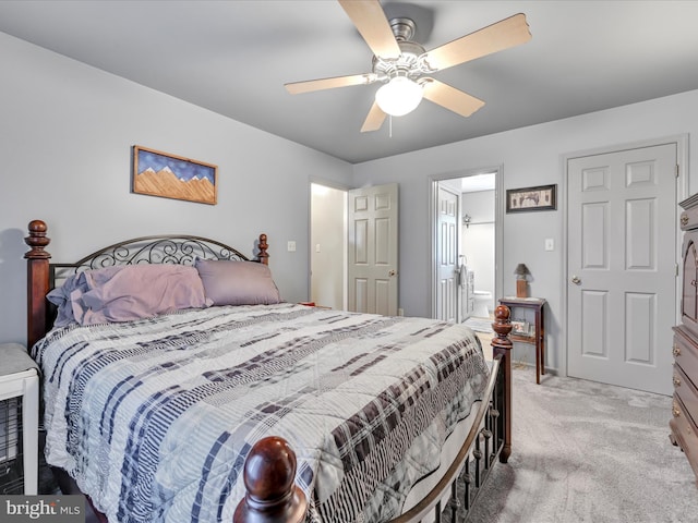 bedroom featuring light colored carpet, ensuite bathroom, and a ceiling fan