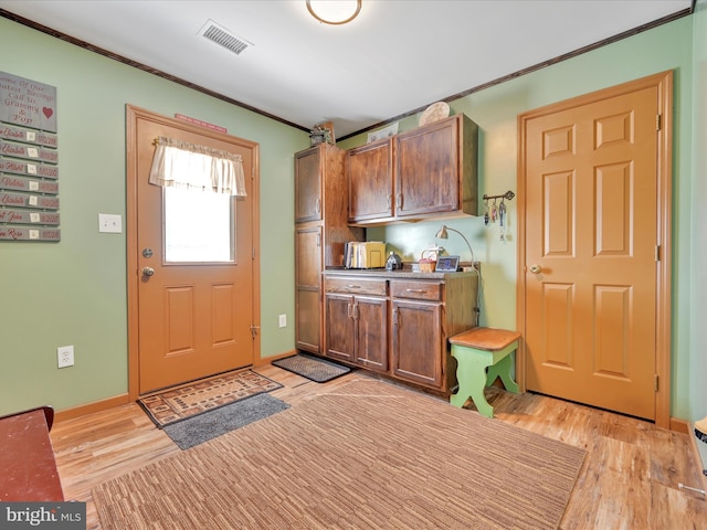 kitchen with crown molding, baseboards, visible vents, and light wood finished floors