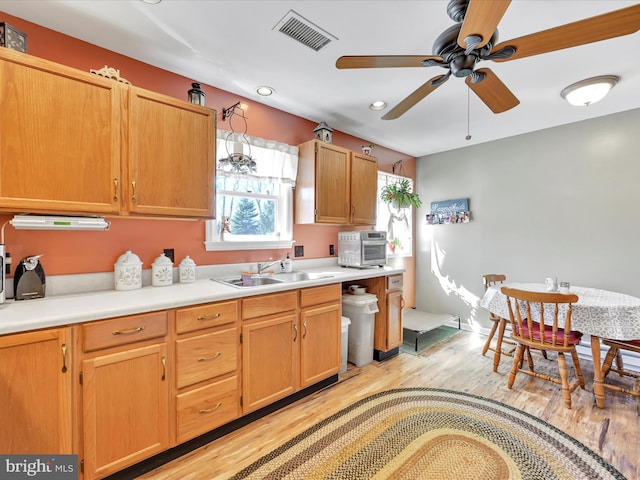 kitchen with light countertops, visible vents, light wood finished floors, and a sink