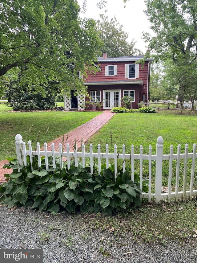 view of front facade featuring a fenced front yard, french doors, a chimney, and a front yard