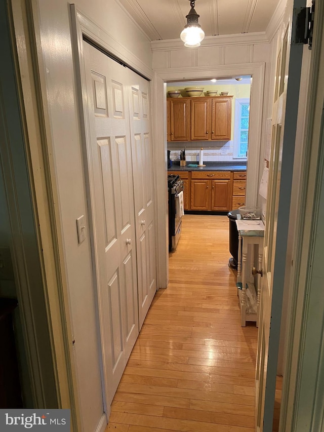 corridor featuring light wood-style flooring and ornamental molding