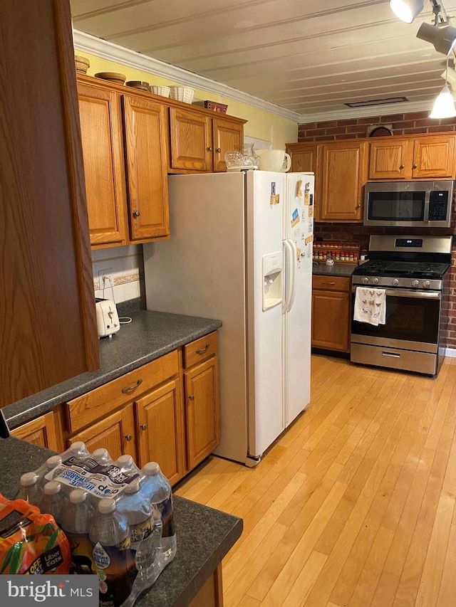 kitchen with light wood-style flooring, ornamental molding, appliances with stainless steel finishes, dark countertops, and brown cabinets