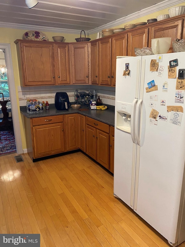 kitchen featuring crown molding, light wood-style flooring, white refrigerator with ice dispenser, and brown cabinets