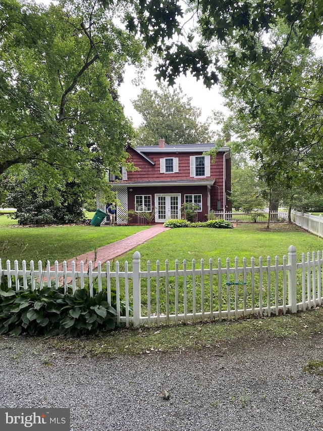 view of front facade featuring a front lawn, french doors, a fenced front yard, and a chimney