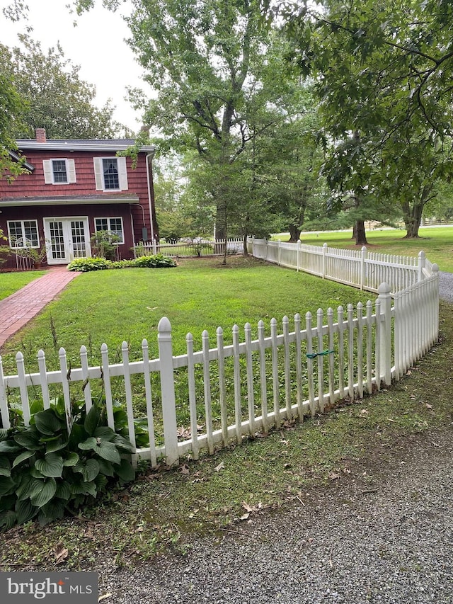 view of front of house with french doors, fence private yard, and a front lawn