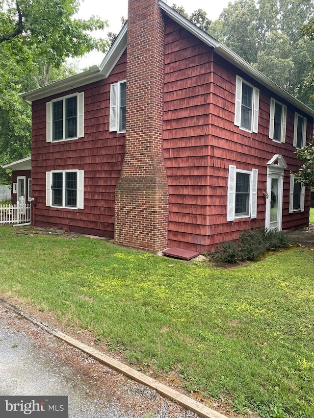 view of side of property with a lawn and a chimney