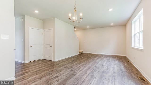 empty room with wood finished floors, baseboards, visible vents, recessed lighting, and a chandelier