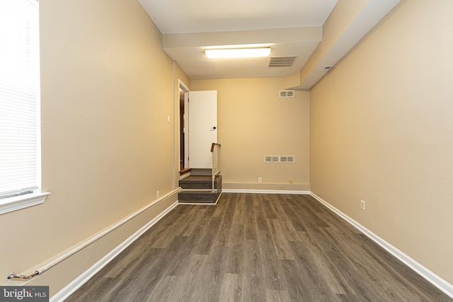 unfurnished room featuring dark wood finished floors, visible vents, and baseboards