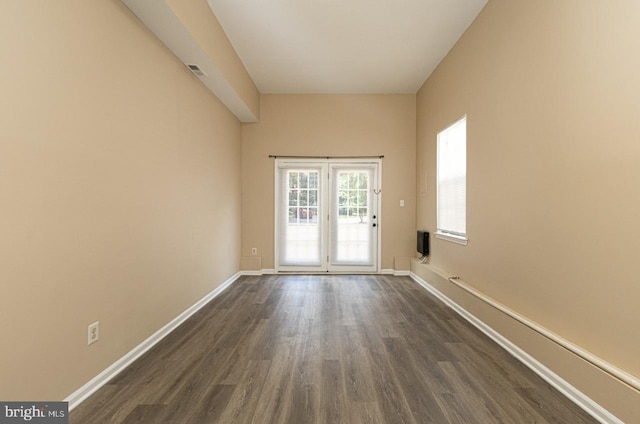 spare room featuring visible vents, baseboards, and dark wood-style flooring