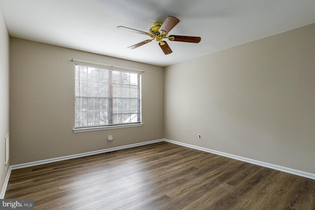 unfurnished room with ceiling fan, visible vents, baseboards, and dark wood finished floors