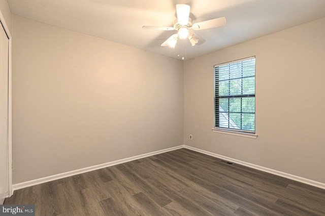 spare room featuring visible vents, baseboards, a ceiling fan, and dark wood-style flooring