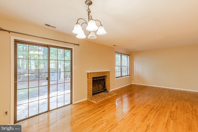 unfurnished living room with visible vents, light wood-style floors, a healthy amount of sunlight, and a notable chandelier