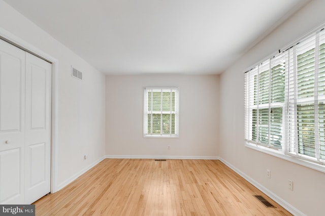 unfurnished room with visible vents, light wood-type flooring, and baseboards