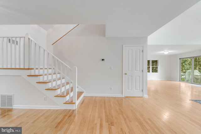 stairs with wood finished floors, visible vents, and baseboards