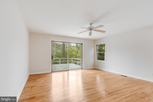 unfurnished room with a ceiling fan, visible vents, light wood finished floors, and baseboards