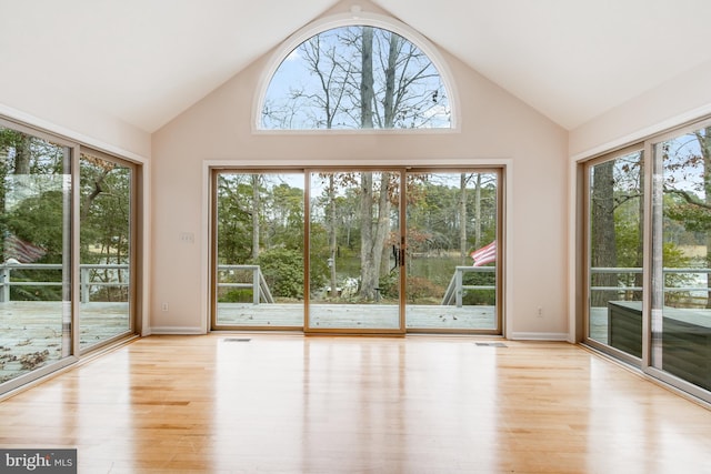 unfurnished sunroom with visible vents, a healthy amount of sunlight, and lofted ceiling