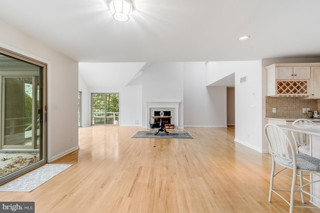 living room with light wood-style flooring, visible vents, and baseboards