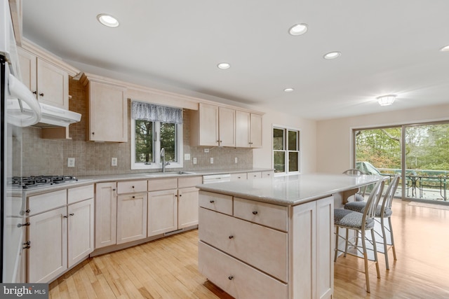 kitchen with a kitchen bar, a sink, a kitchen island, a healthy amount of sunlight, and stainless steel gas cooktop