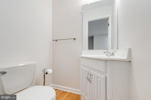 bathroom with baseboards, toilet, wood finished floors, and vanity