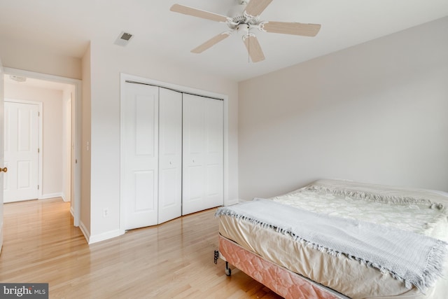 bedroom featuring visible vents, baseboards, light wood-style floors, a closet, and a ceiling fan