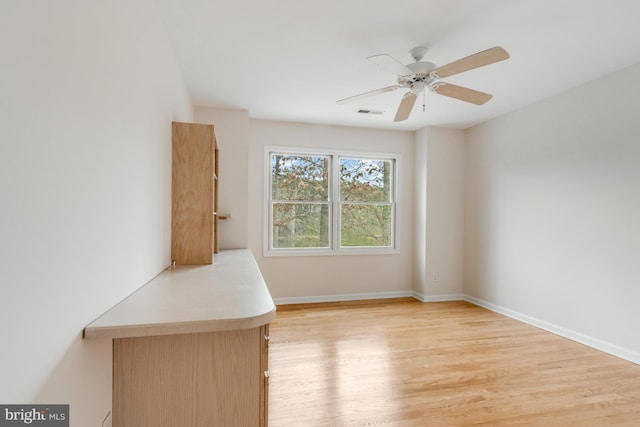 empty room featuring a ceiling fan, baseboards, and light wood finished floors