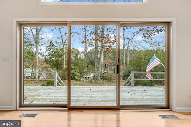 doorway to outside with wood finished floors, visible vents, and baseboards