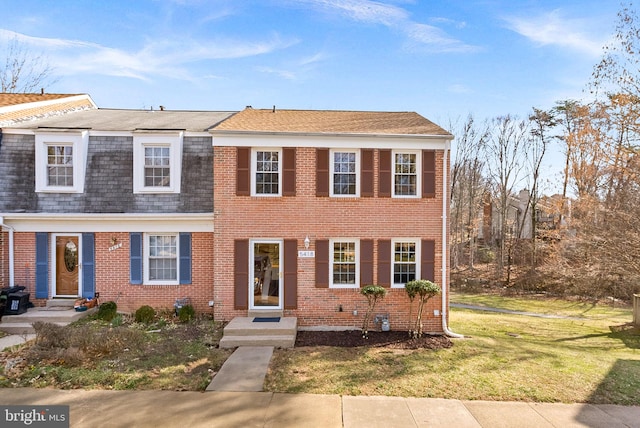 view of front of property with brick siding, a shingled roof, and a front yard