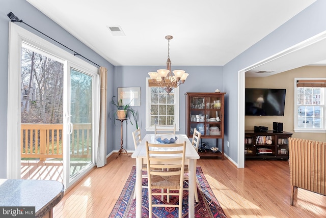 dining area featuring an inviting chandelier, baseboards, visible vents, and light wood finished floors