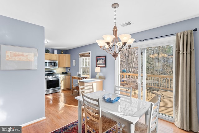 dining space featuring an inviting chandelier, visible vents, and light wood finished floors