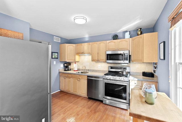 kitchen featuring a sink, stainless steel appliances, backsplash, and light brown cabinets