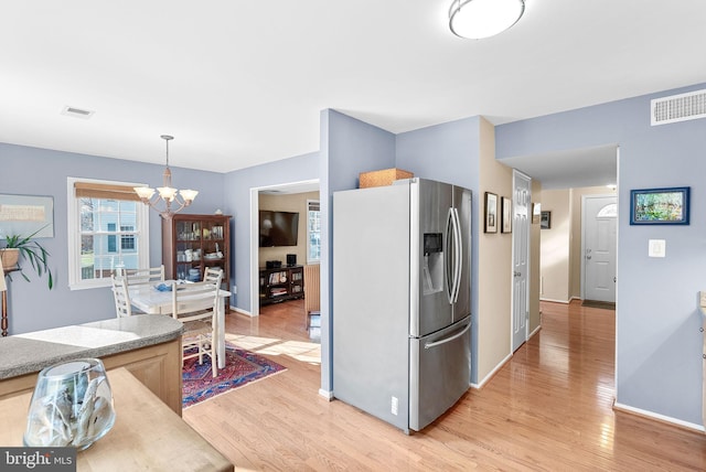 kitchen with visible vents, stainless steel refrigerator with ice dispenser, light wood-style floors, baseboards, and a chandelier